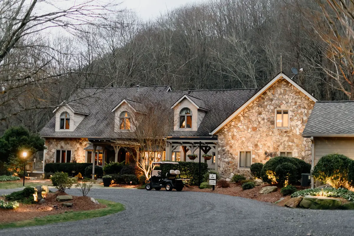 Hawkesdene's stone main house in winter, windows lit