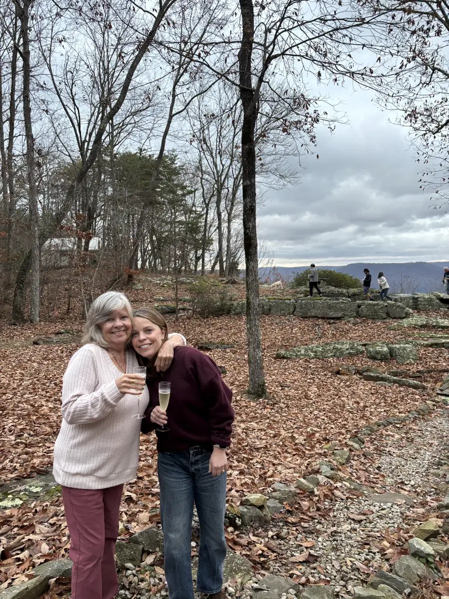 A champagne hug on the leaf-covered overlook, engagement day