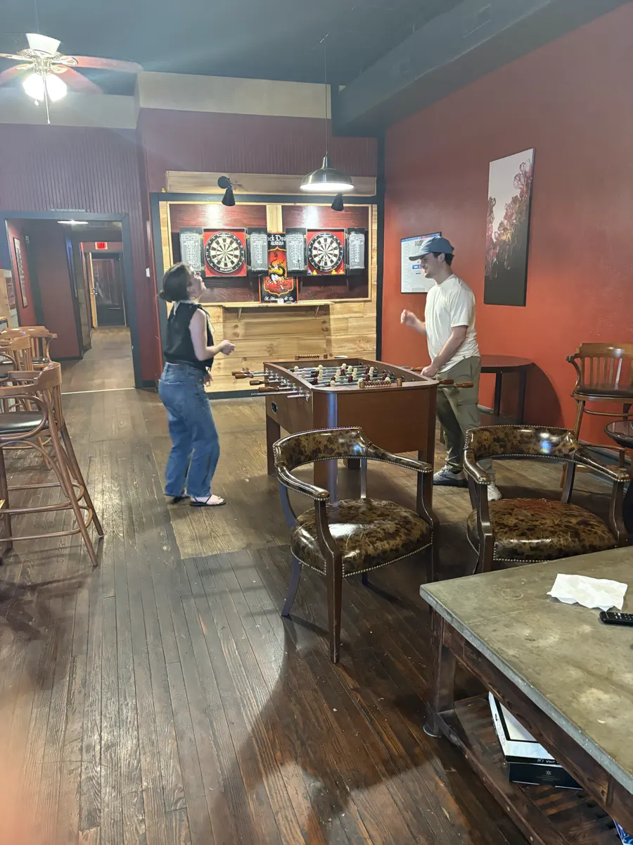 Shelby and Hobey playing foosball under the dart boards at The Tattered Tartan Pub