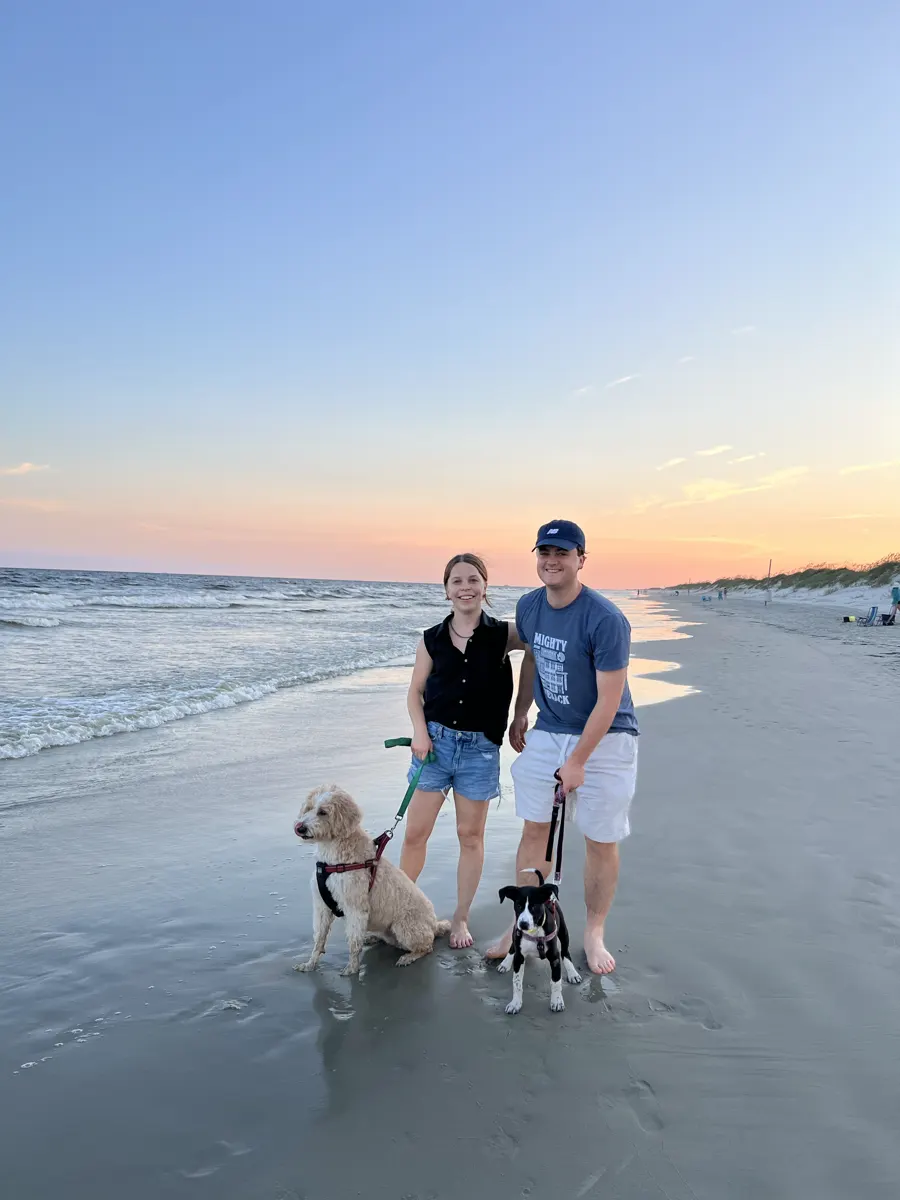Shelby and Hobey walking the dogs on the beach at sunrise