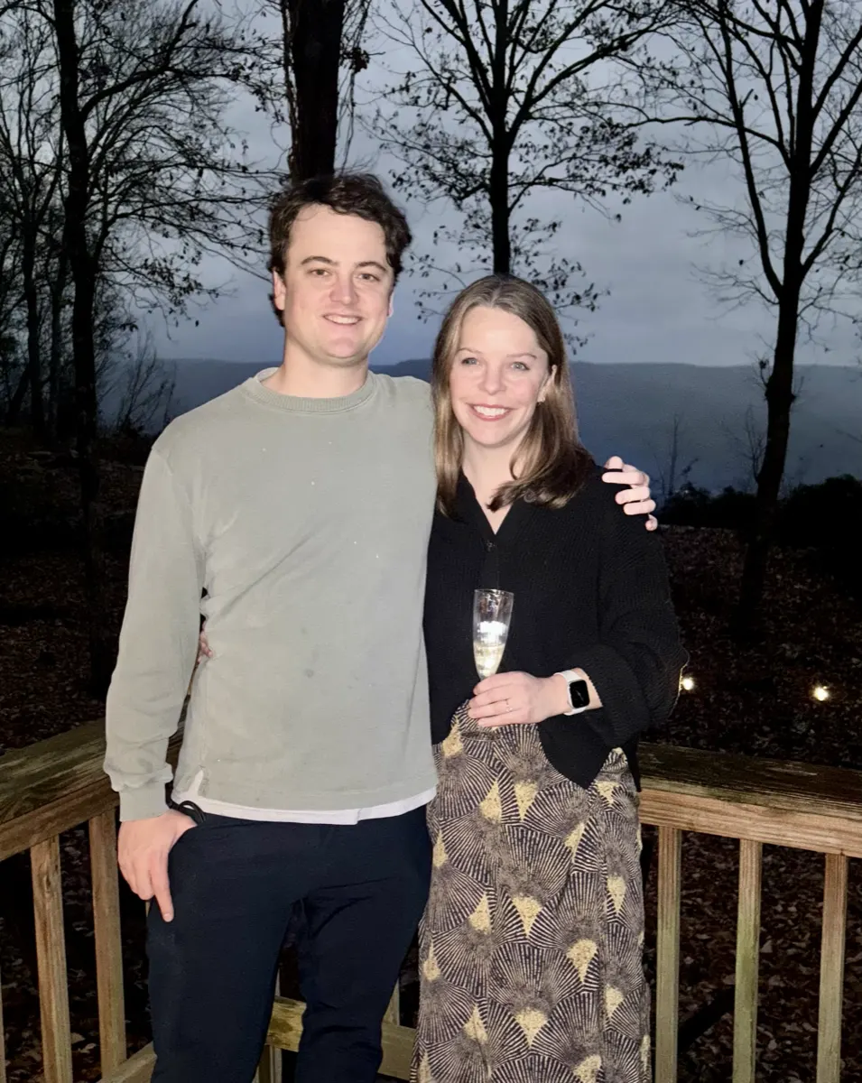 Shelby and Hobey with champagne on the deck at dusk, engagement day
