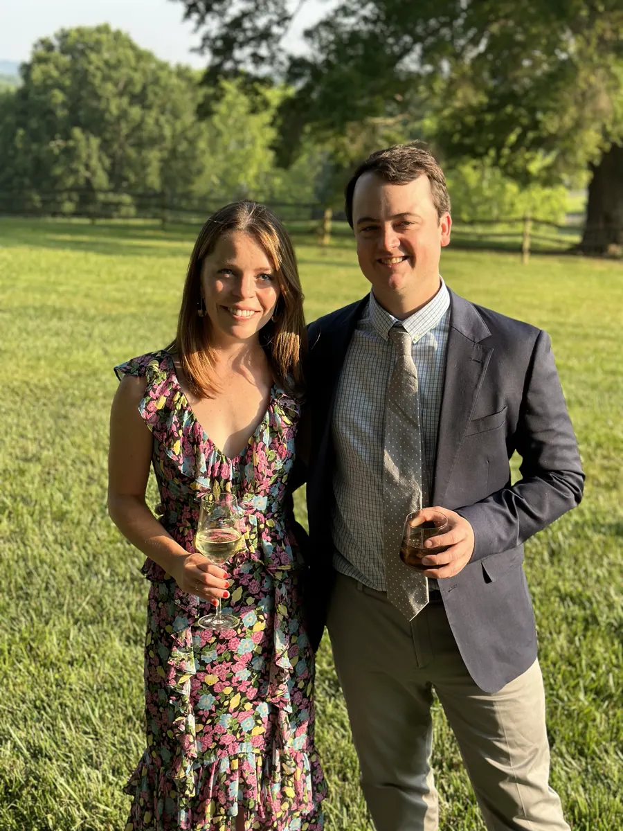 Shelby and Hobey with drinks on a lawn at a summer party