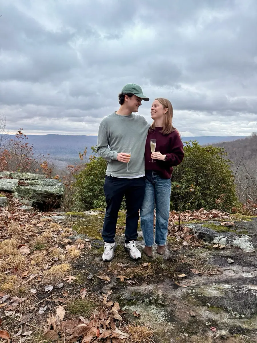 Shelby and Hobey toasting with champagne at a mountain overlook, just after getting engaged